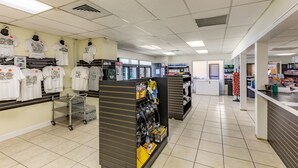 A retail store with shelves of white t-shirts, a display of cleaning supplies, and a Coca-Cola refrigerator.