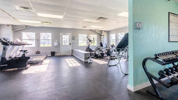 A gym with treadmills, elliptical machines, and a rack of dumbbells.