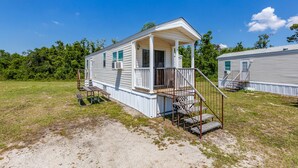 A single-story mobile home with a porch and a small set of stairs leading to the entrance.