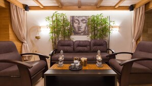 Un salon moderne avec un canapé en cuir marron, deux fauteuils marron, une table basse en bois et une statue de Bouddha.