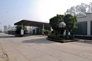 A covered outdoor area with a sign, potted plants, and a spherical sculpture. - Mapple Exotica (New Delhi)
