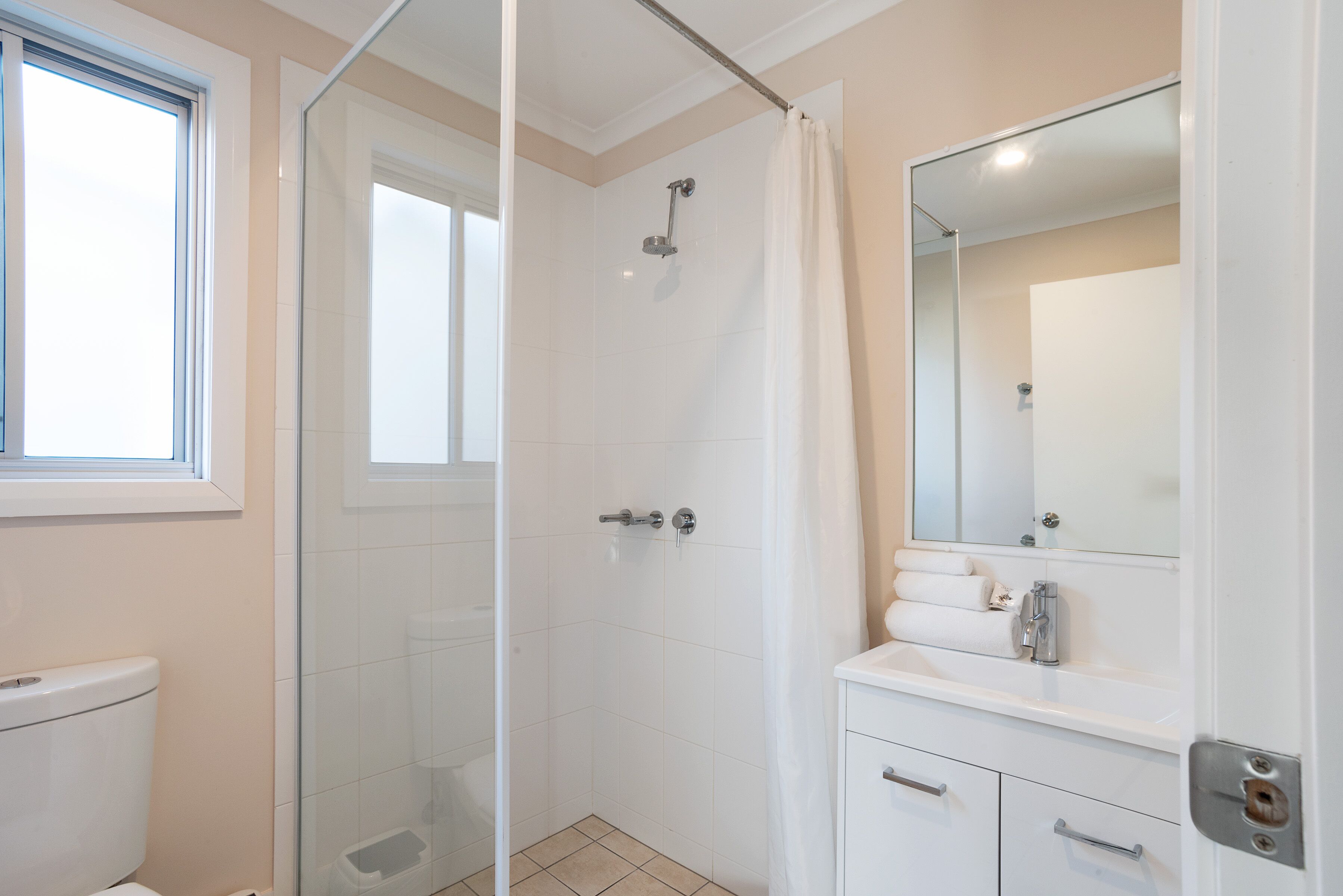 A bathroom with a glass shower enclosure, a toilet, and a vanity with a mirror.