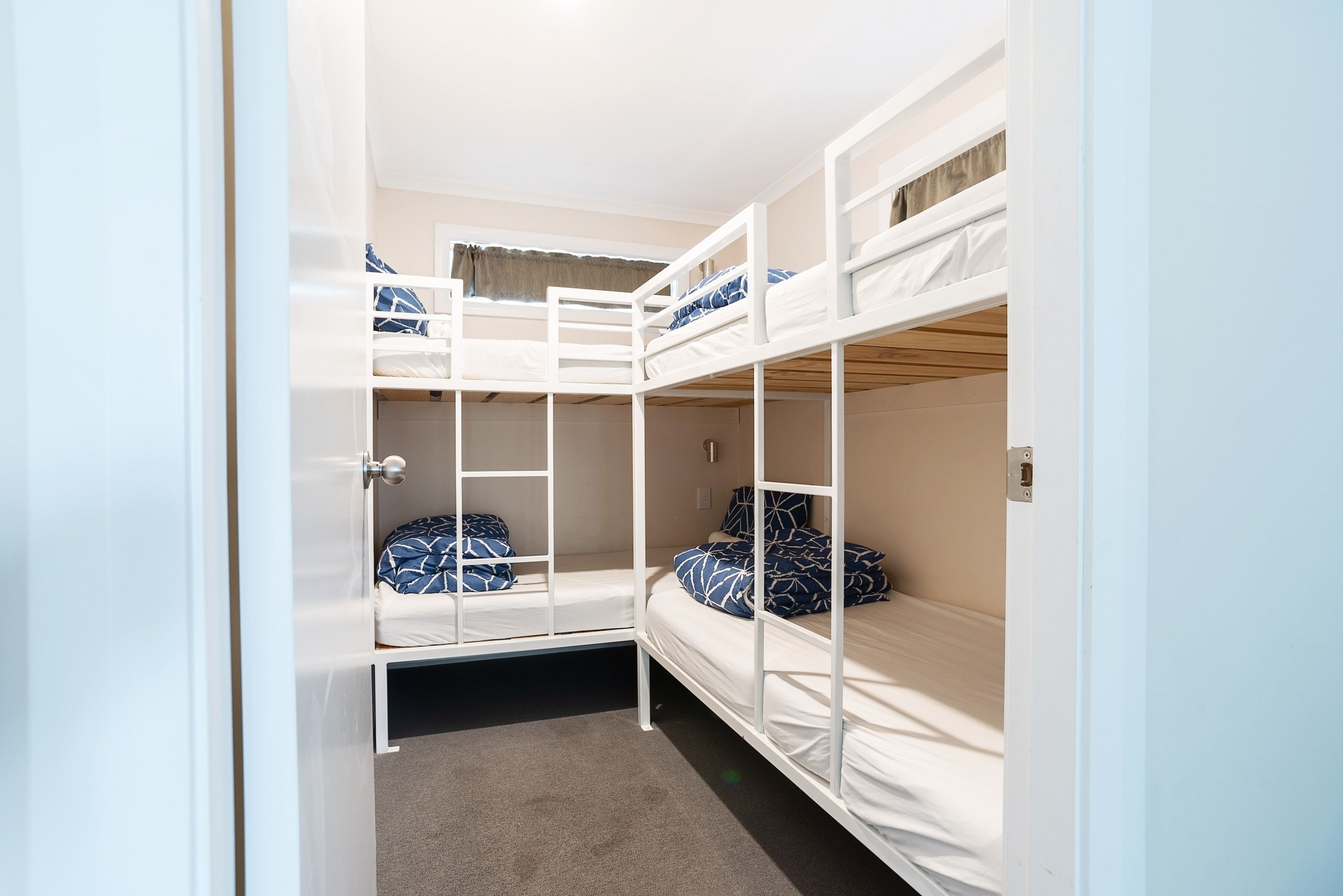 A bunk bed room with white railings and blue patterned pillows.