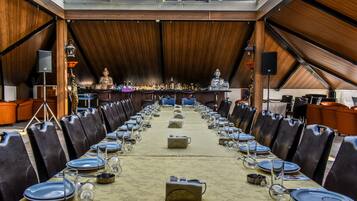 A long dining table set for a banquet in a room with wooden walls and a high ceiling.