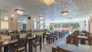A spacious dining area with multiple tables and chairs, large windows, and a ceiling with decorative lighting fixtures. - Al Murjan Palace Hotel (Jounieh)