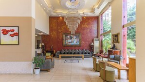 A spacious lobby with a large sofa, a wooden coffee table, and a potted plant. - Al Murjan Palace Hotel (Jounieh)