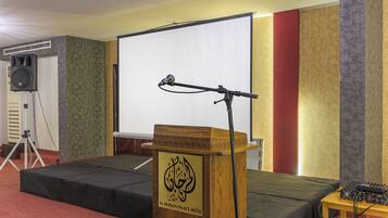 A conference room with a podium, a microphone, a projector screen, and a speaker.