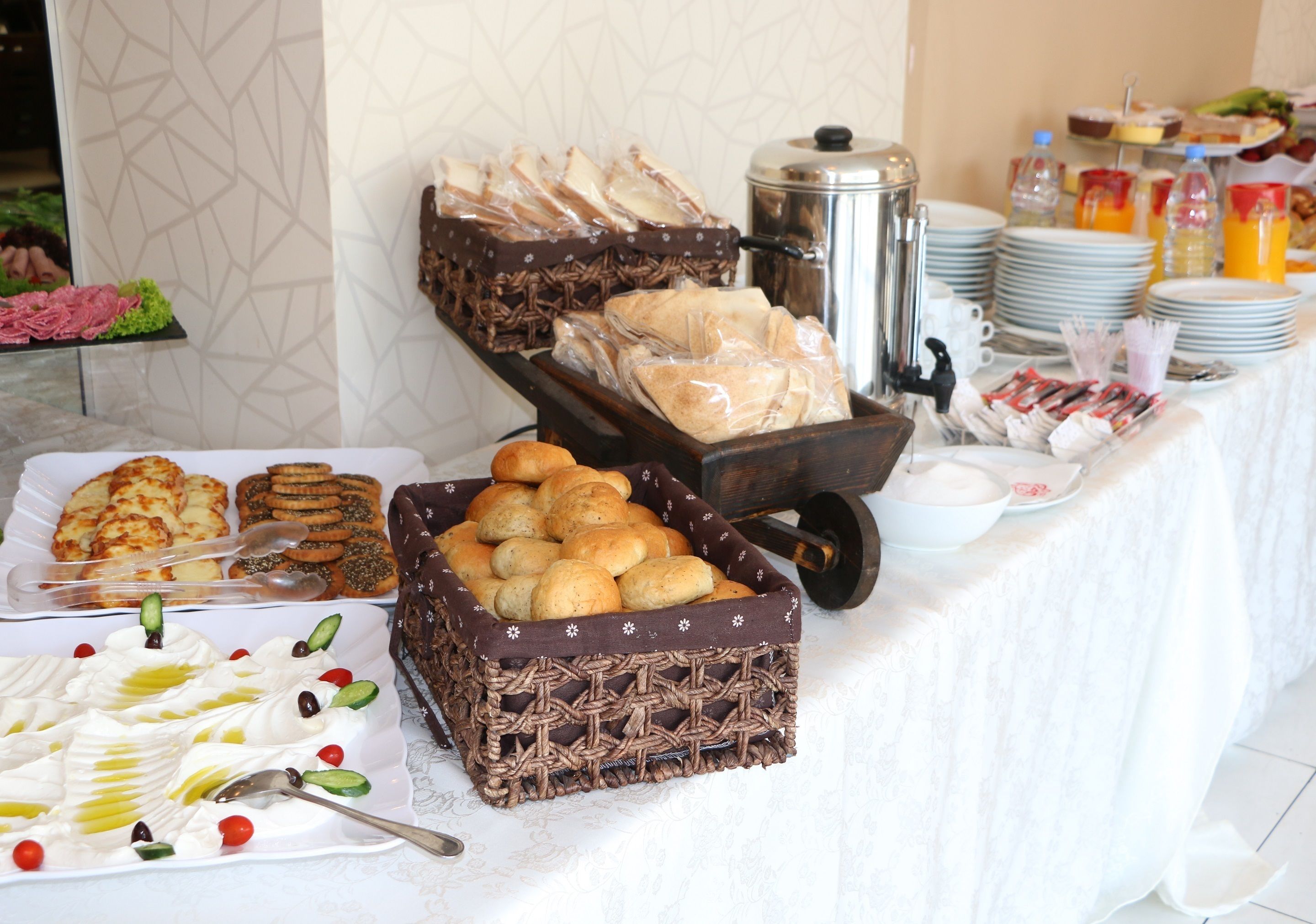 Taula de buffet amb diversos aliments, com ara pa, pastissos i una selecció de begudes.