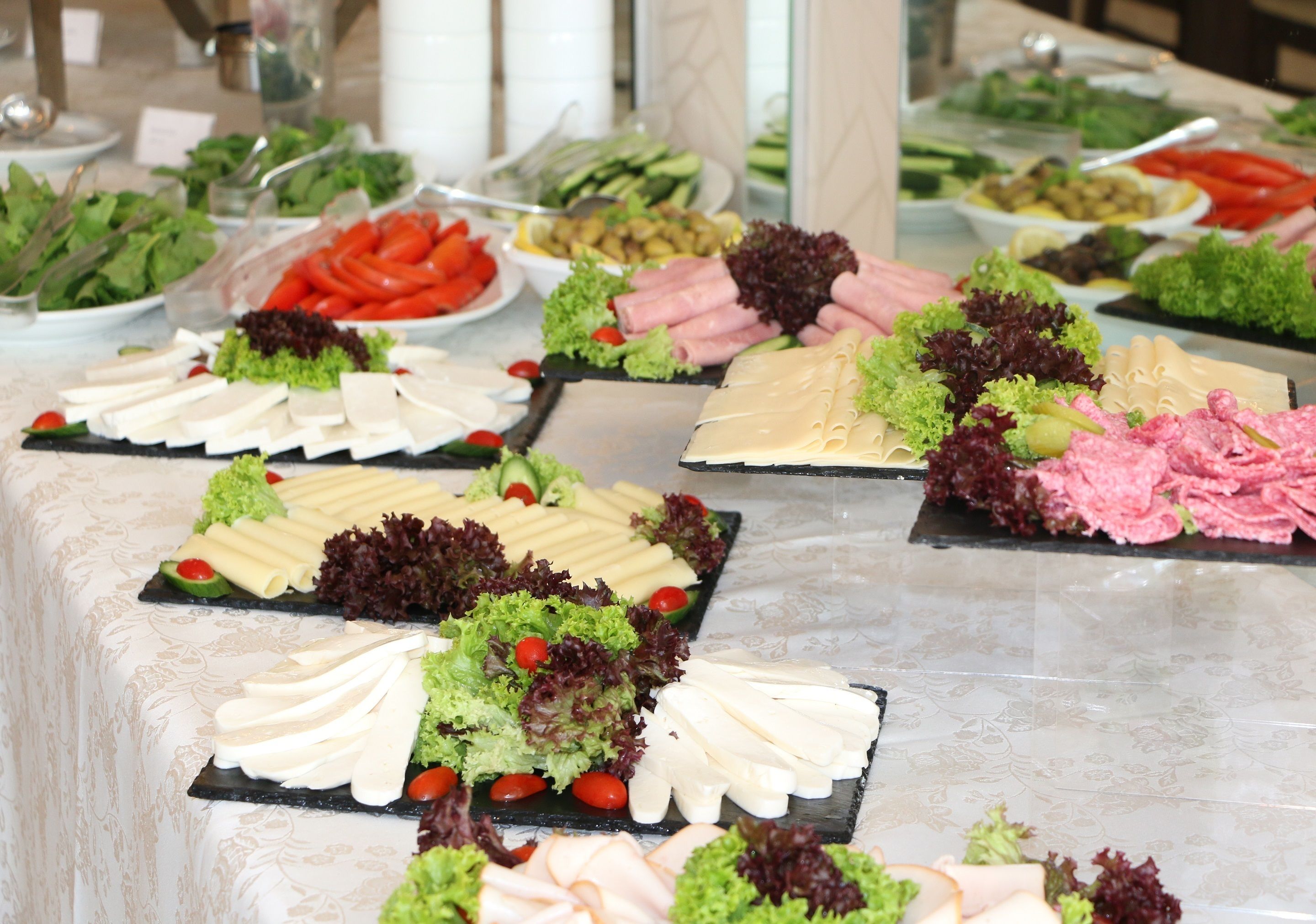 A buffet table with various food items including meats, cheeses, and vegetables.