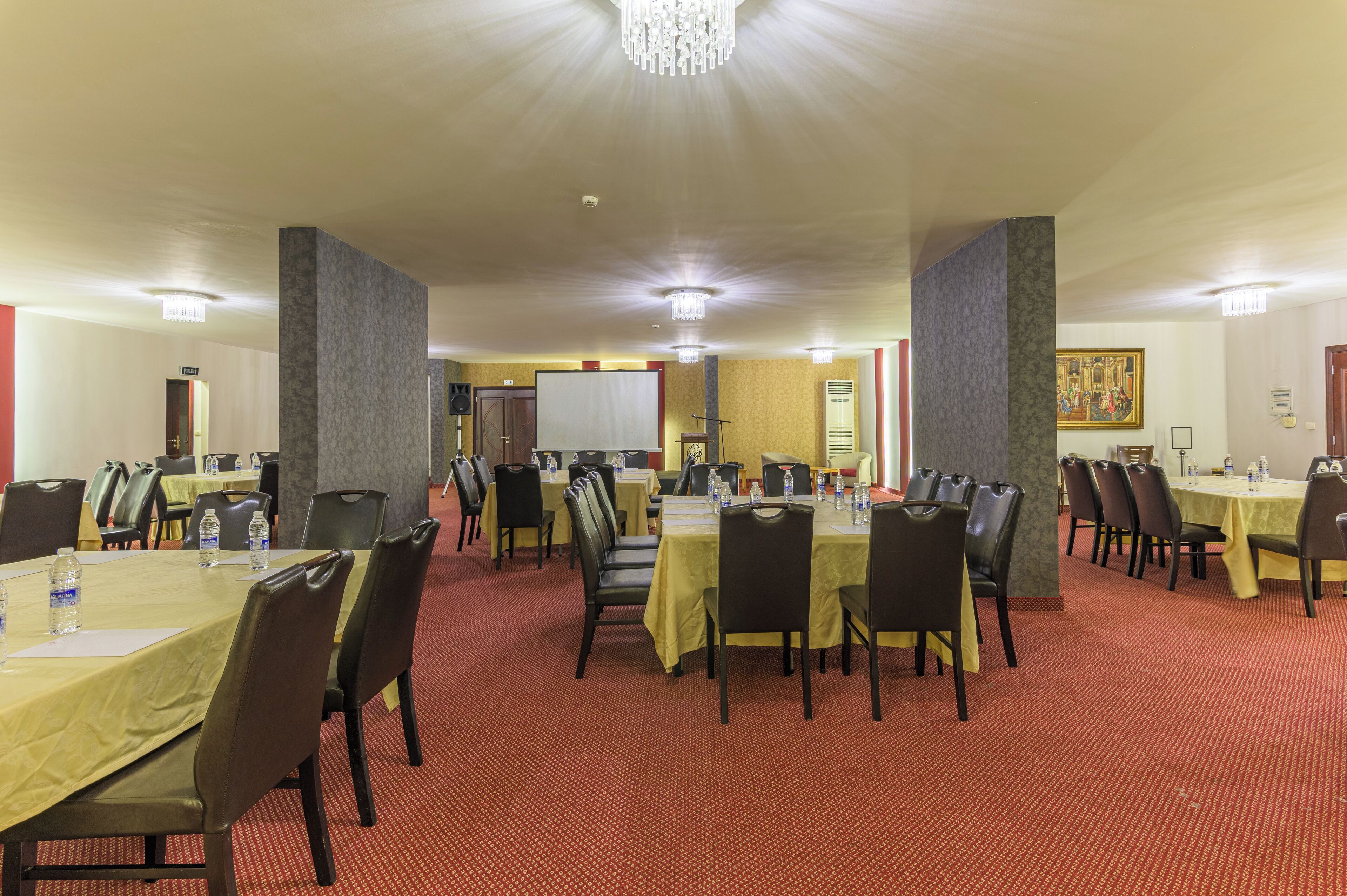 A conference room with multiple tables and chairs, equipped with water bottles and nameplates.