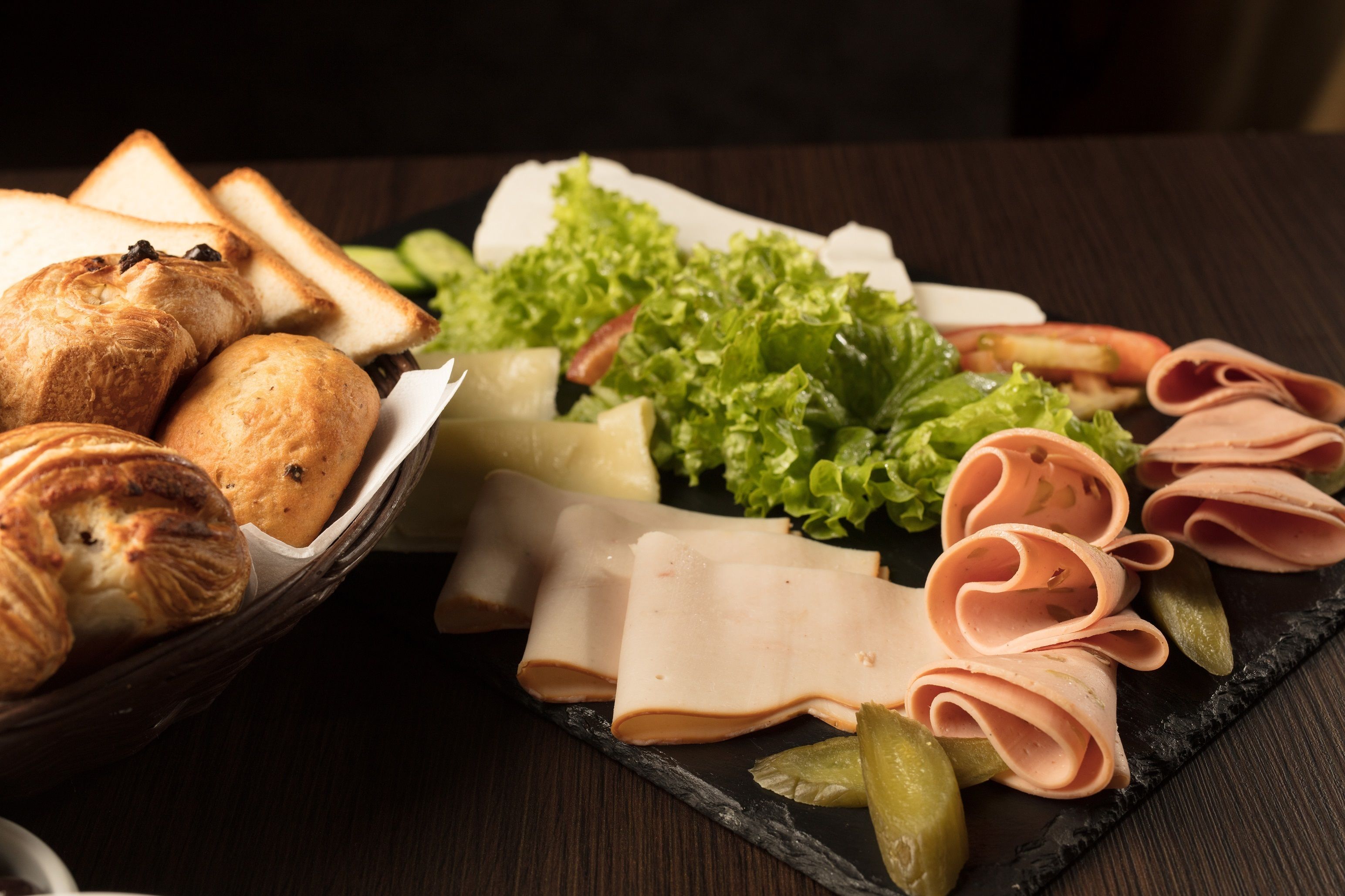 A charcuterie board with various meats, cheeses, and bread.