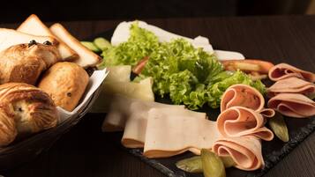 A charcuterie board with various meats, cheeses, and bread.