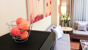 A modern hotel room with a black table, a grey sofa, and a wall with abstract art.