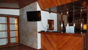 A reception desk with a television mounted above it, a sign reading "Pacific Dreams," and a tiled wall. - Pacific Dreams (Panama City)