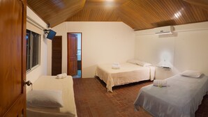 A room with two beds, a wooden ceiling, a TV, and a door leading to another room. - Pacific Dreams (Panama City)