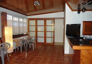 Una cocina con techo de madera, un televisor y un comedor con sillas y una mesa.
