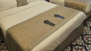A hotel room with two beds, a brick wall with a decorative archway, a window with curtains, and a patterned carpet. - A Plus Residence (Istanbul)