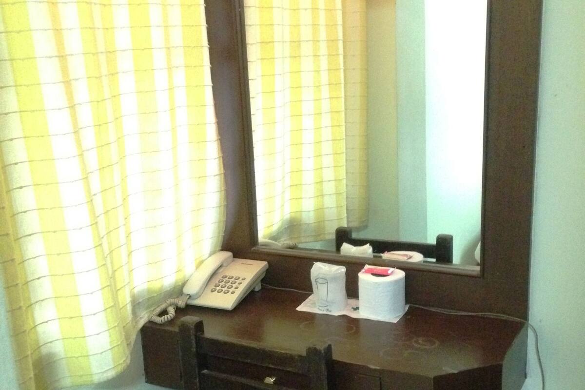 Uma pequena mesa com um telefone, um espelho e uma caixa de lenços.