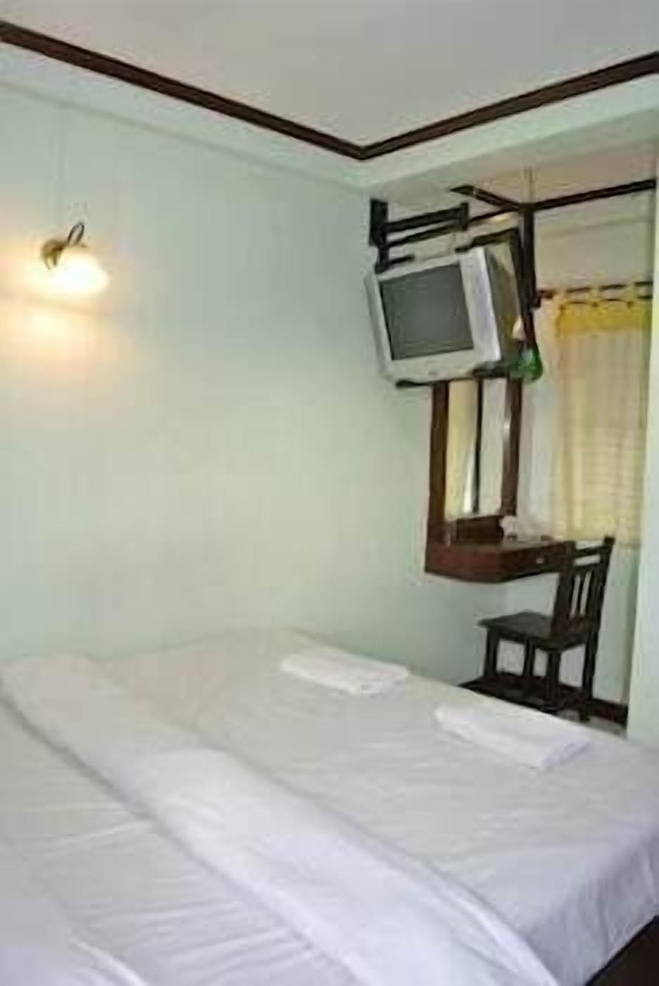 Una stanza con un letto, una scrivania con un monitor computer e una sedia.