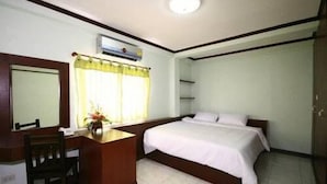 A hotel room with a bed, a desk, a chair, a mirror, and a window with curtains.