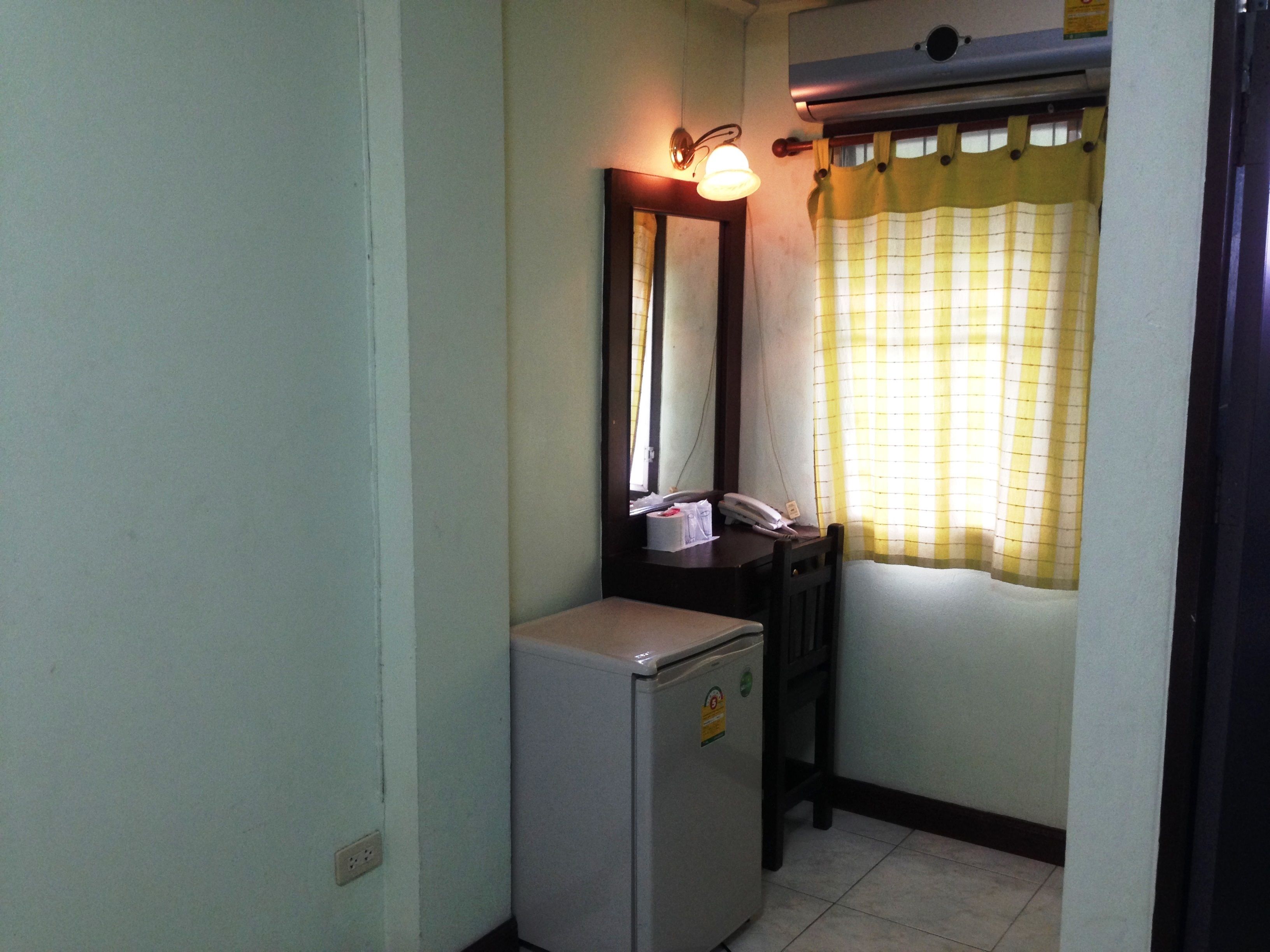 A small, compact bathroom with a toilet, a sink, a mirror, and a refrigerator.