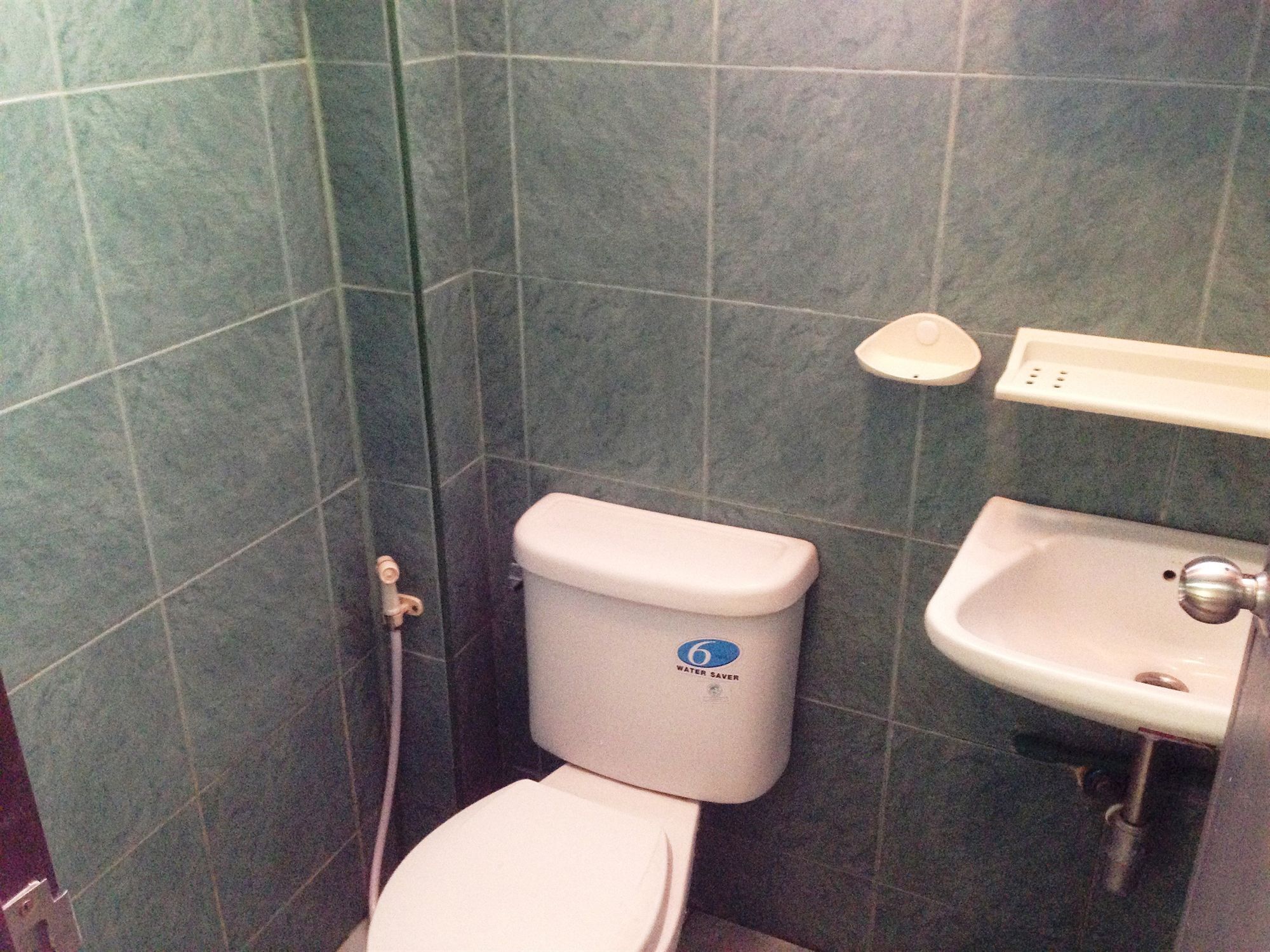A bathroom with a toilet, a sink, and a water-saving device.
