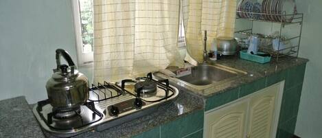 A kitchen with a gas stove, a sink, and a dish rack.