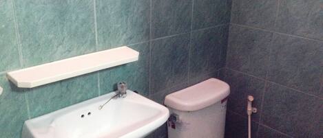 A bathroom with a white sink, toilet, and a shelf above the sink.
