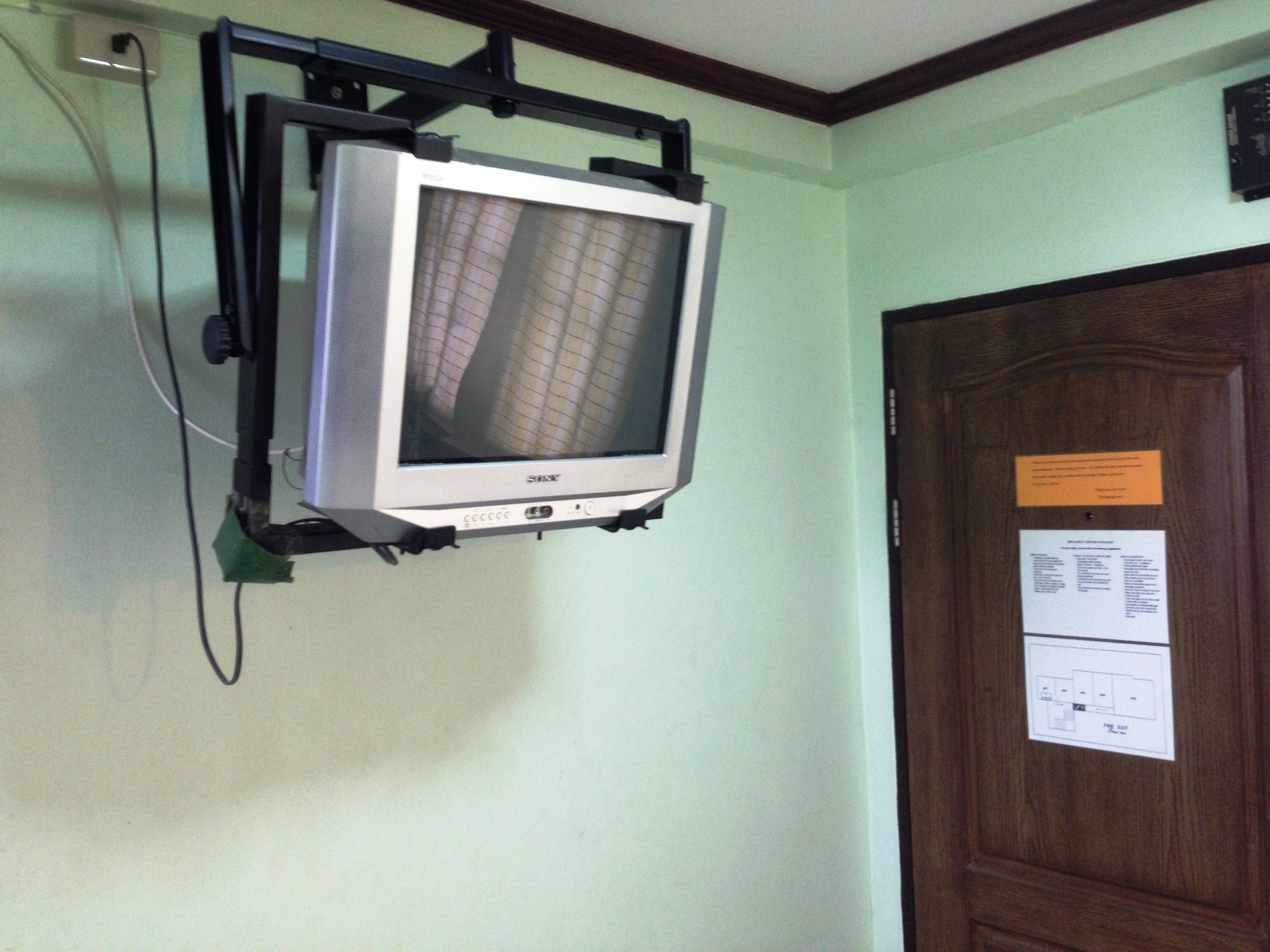 A television mounted on a wall with a wooden door nearby.