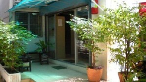 A courtyard with potted plants, a blue awning, and a door leading to a building.