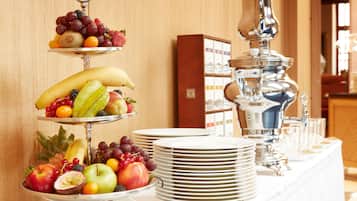Una mesa de buffet con varias fuentes de fruta y una tetera de plata.