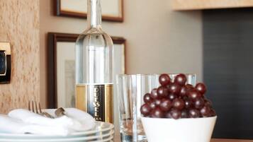 Una mesa con una botella, una copa y un cuenco de uvas.