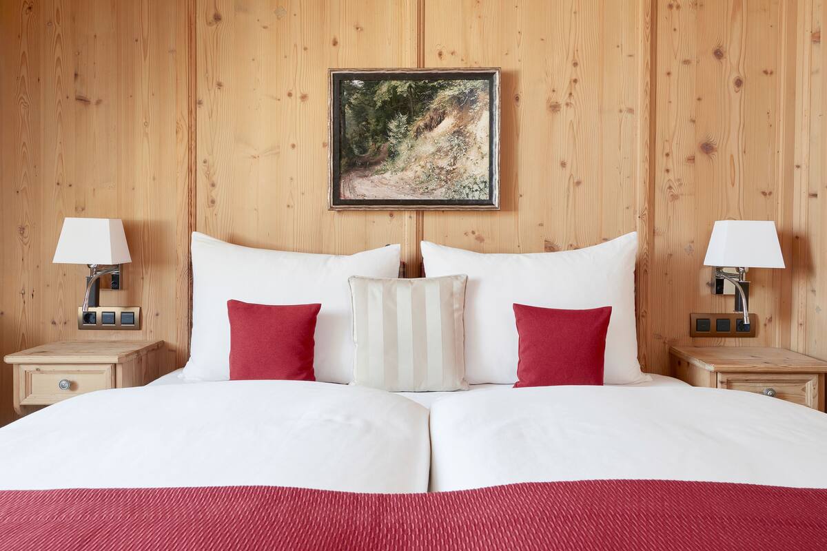 Una habitación con paneles de madera, una cama, dos mesitas de noche y un cuadro en la pared.