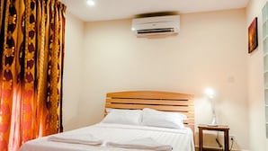 A hotel room with a bed, an air conditioning unit, a bedside lamp, and a curtain. - J'adore Lodge (Phnom Penh)