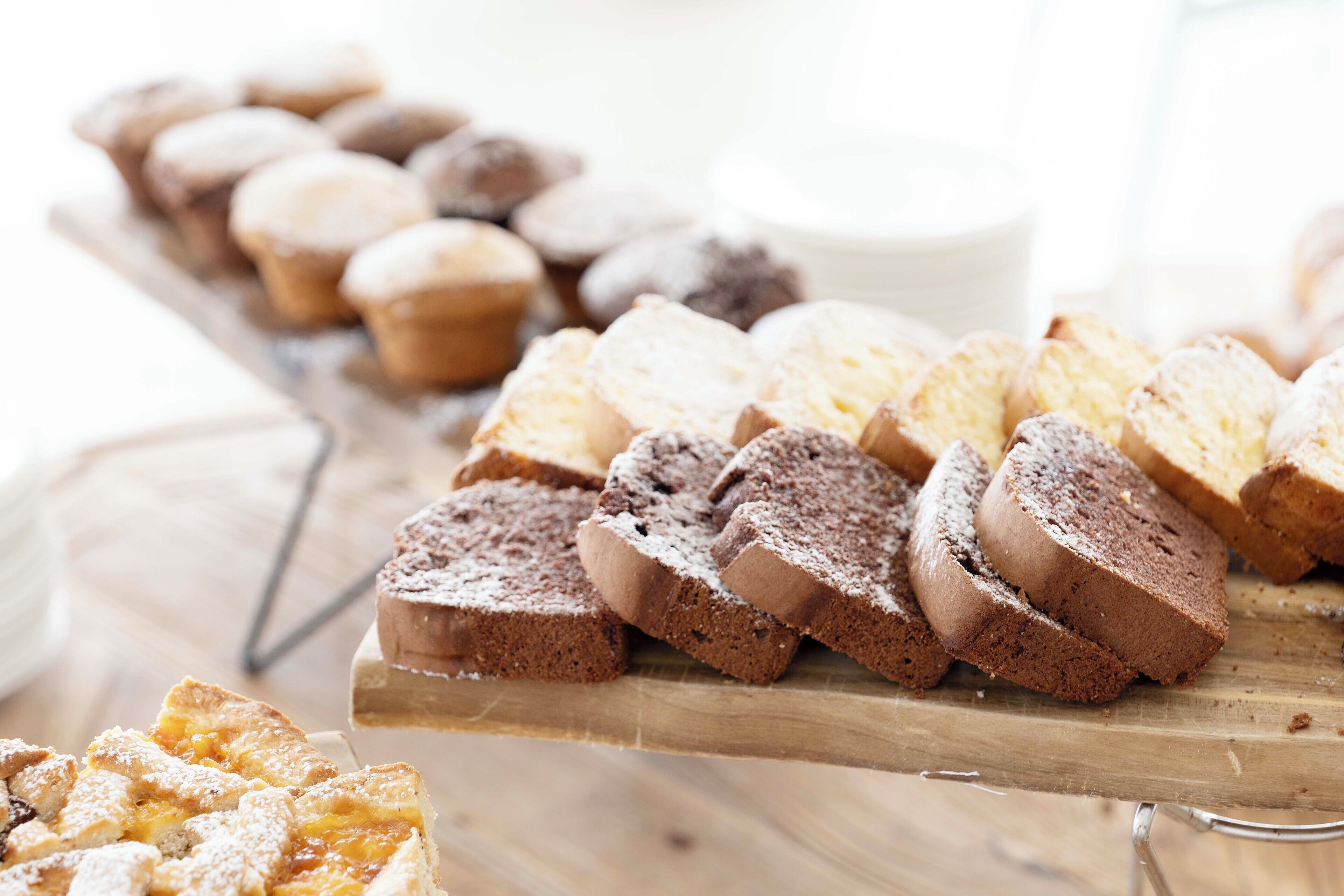 Une variété de viennoiseries présentées sur une planche en bois, notamment des muffins et des parts de gâteau.