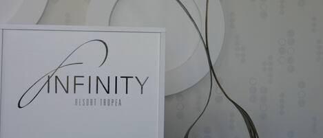 A sign with the text "INFINITY RESORT TROPEA" and a modern abstract sculpture.