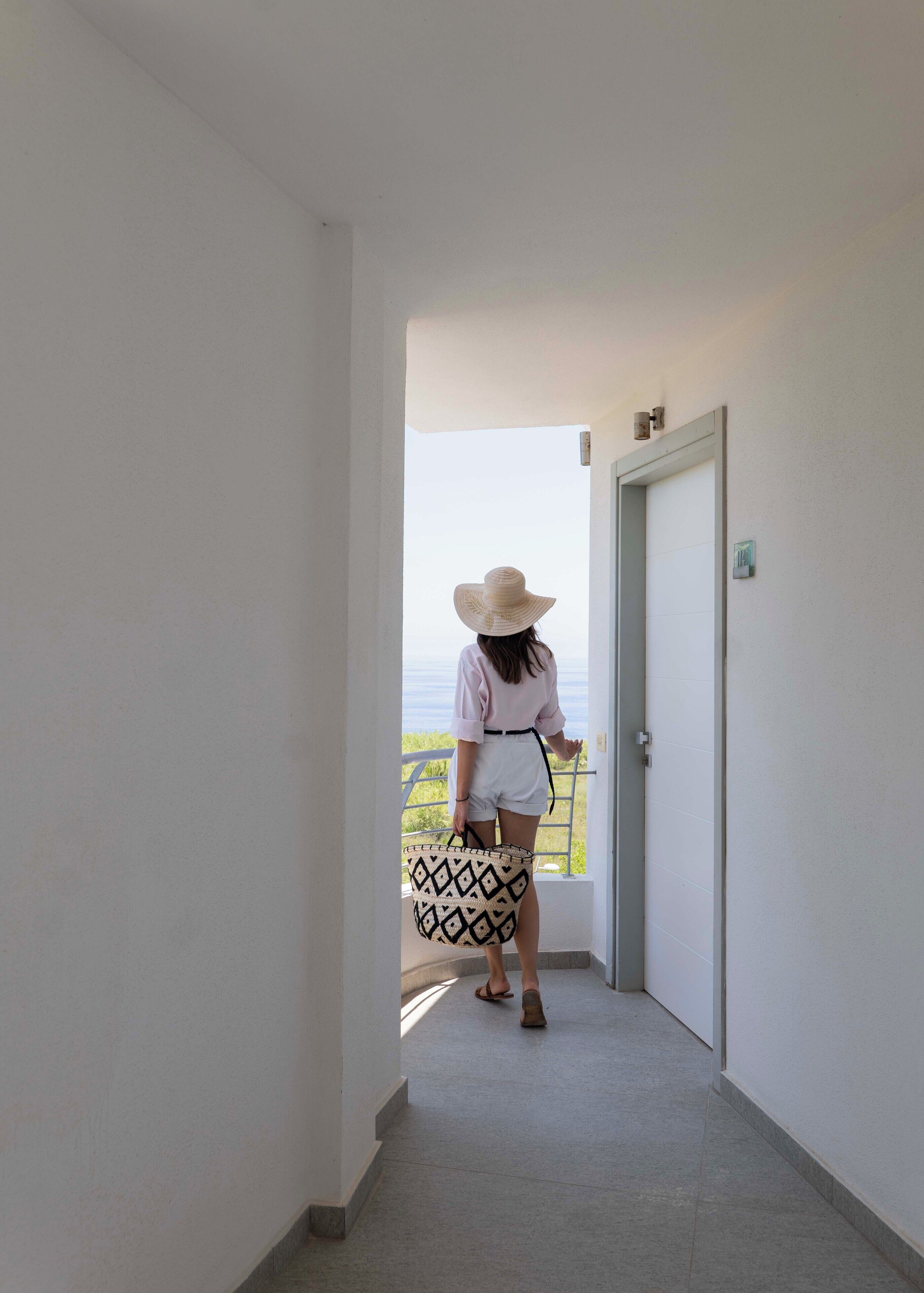 A person walking down a corridor towards a door with a balcony.