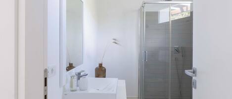 Une salle de bain moderne avec un meuble-lavabo blanc, une douche en verre et des toilettes blanches.