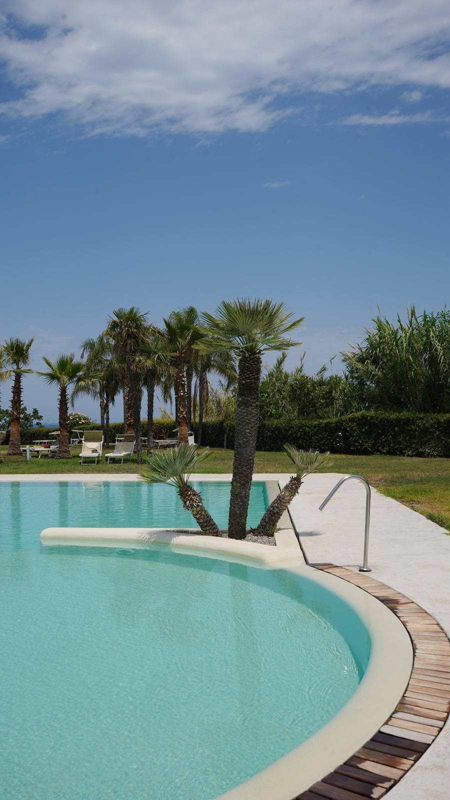 A swimming pool with palm trees and lounge chairs.