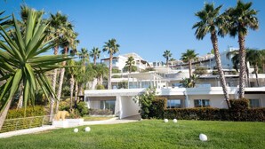 A modern multi-story hotel with a well-maintained lawn and palm trees. - Infinity Resort Tropea (Parghelia)
