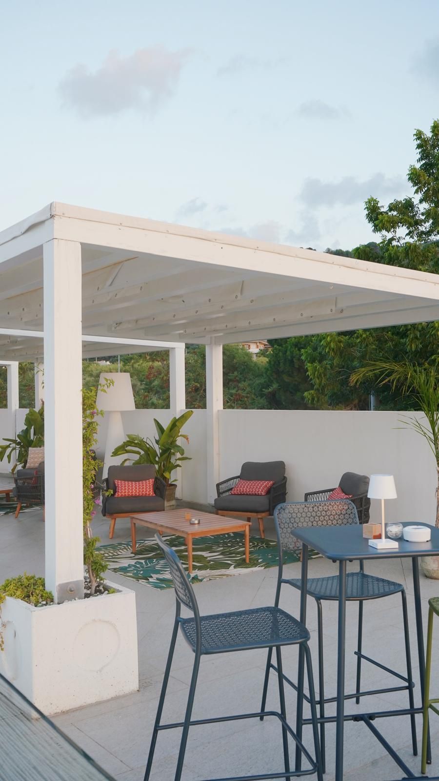 Un patio al aire libre con una zona cubierta para sentarse, una mesa y sillas.