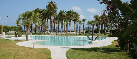 A swimming pool surrounded by palm trees and lounge chairs.