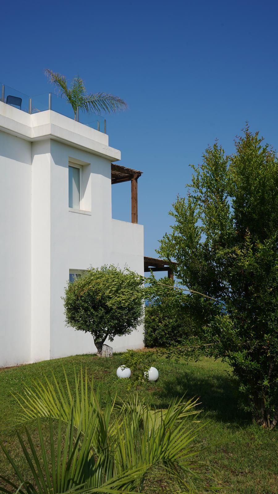 A modern two-story building with a flat roof, large windows, and a small balcony.