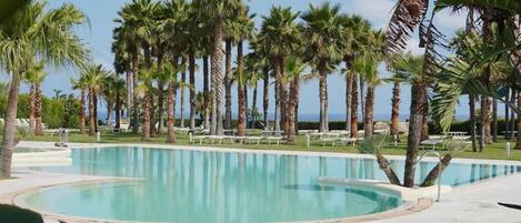 A pool area with palm trees and lounge chairs.