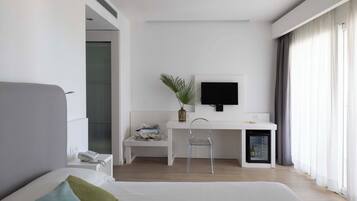 Een moderne hotelkamer met een bed, een bureau, een stoel, een televisie en een kleine koelkast.