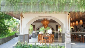 An outdoor dining area with a table and chairs, surrounded by greenery and hanging plants. - The Artini Dijiwa Ubud (Ubud)