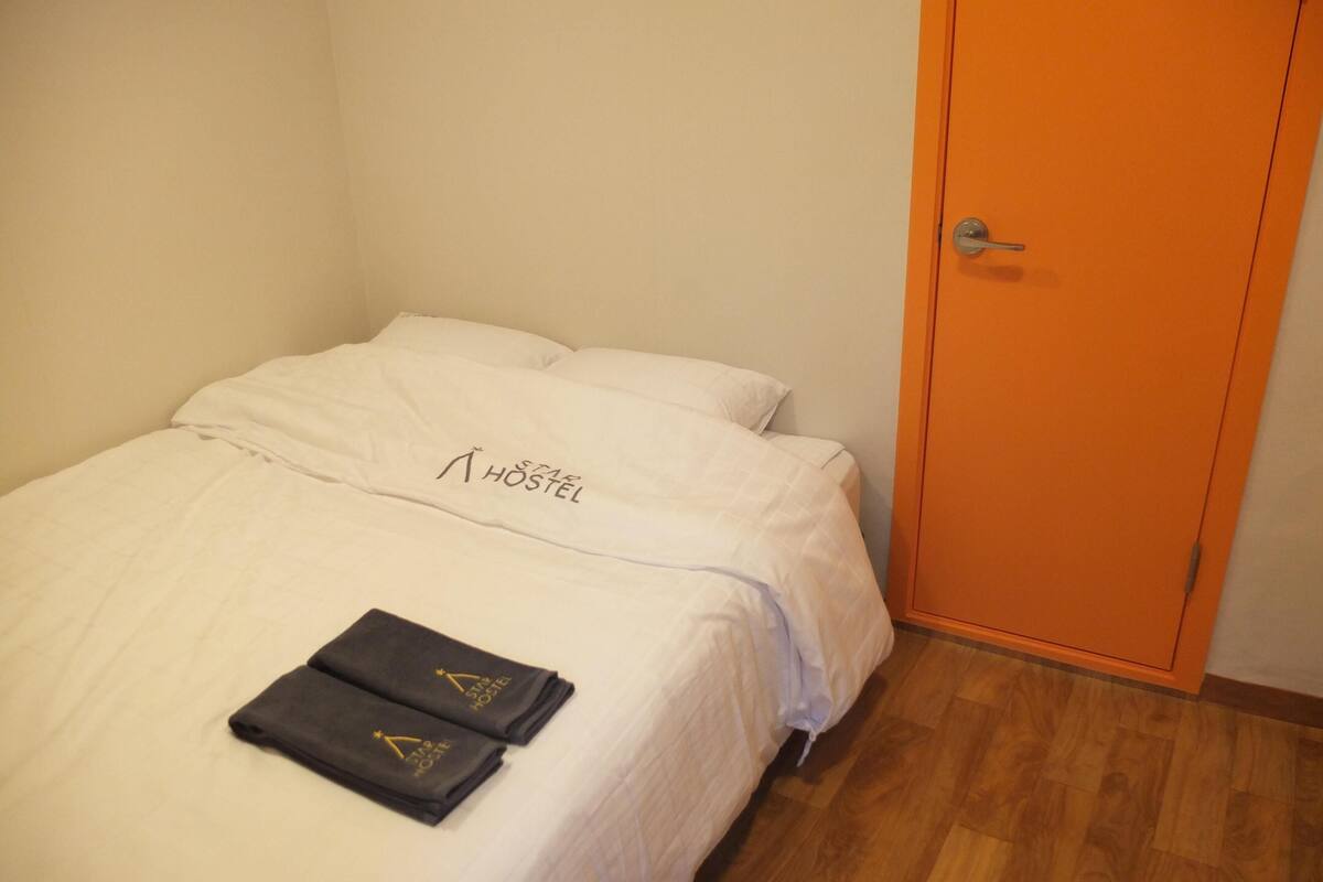 Una cama individual con edredón blanco y dos toallas dobladas con un logotipo.