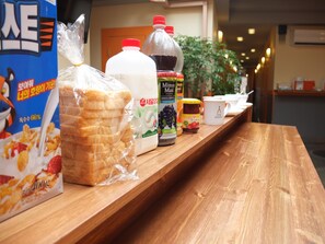 A wooden counter with packaged food items, including a cereal box, a milk carton, a juice bottle, and a jar of honey.