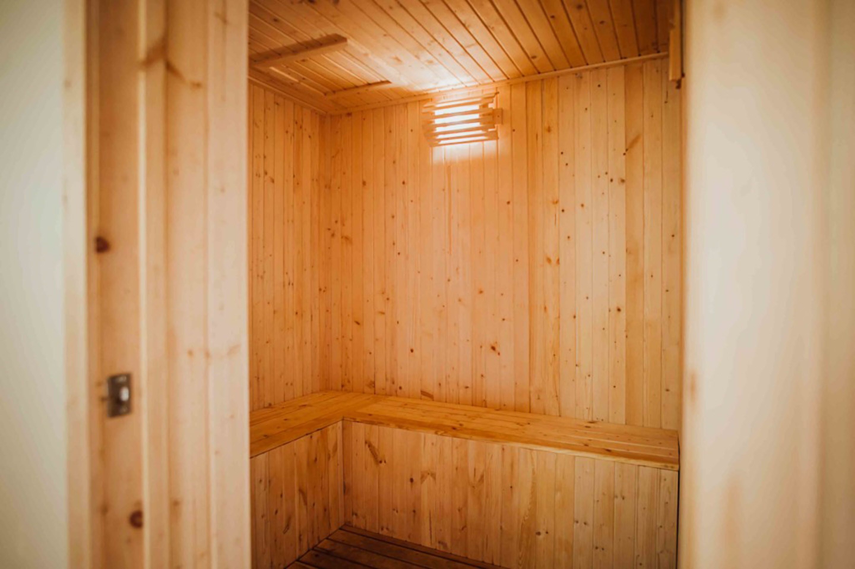 Un sauna en bois avec un banc et un plafond incliné.