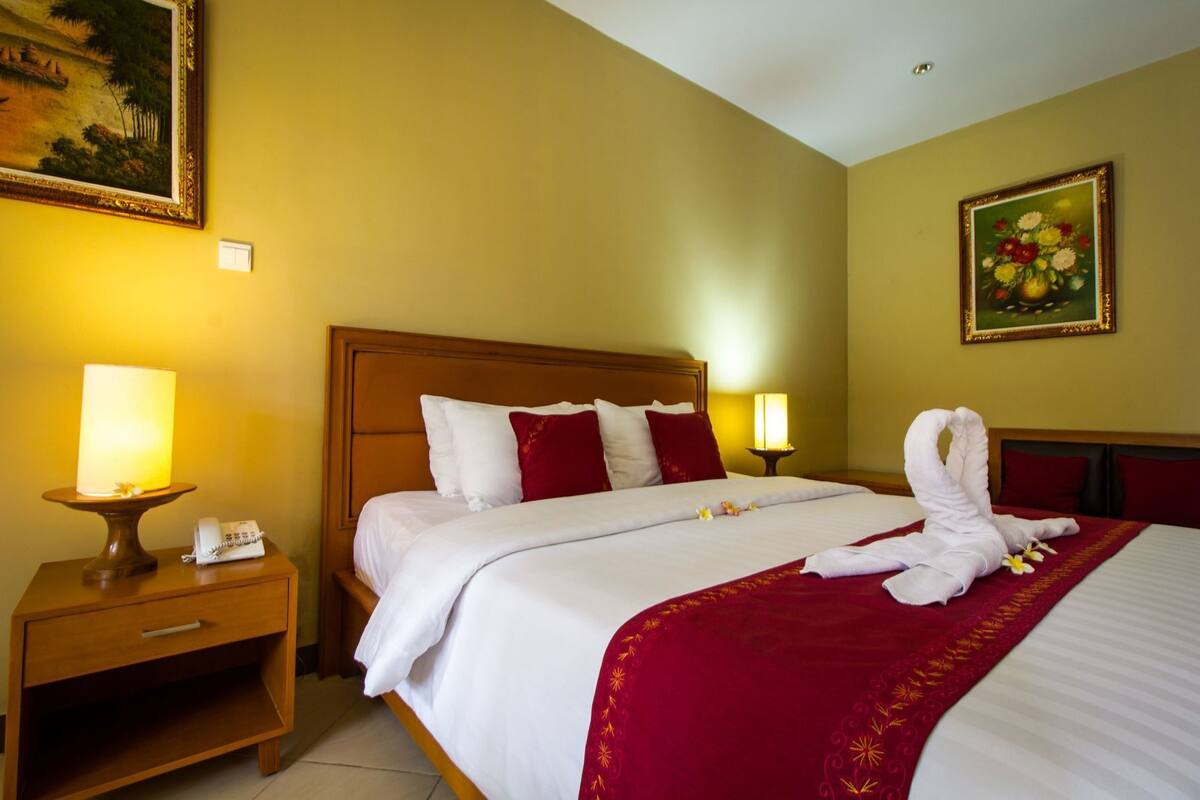 A hotel room with a bed, bedside lamps, a nightstand, a telephone, and artwork on the walls.
